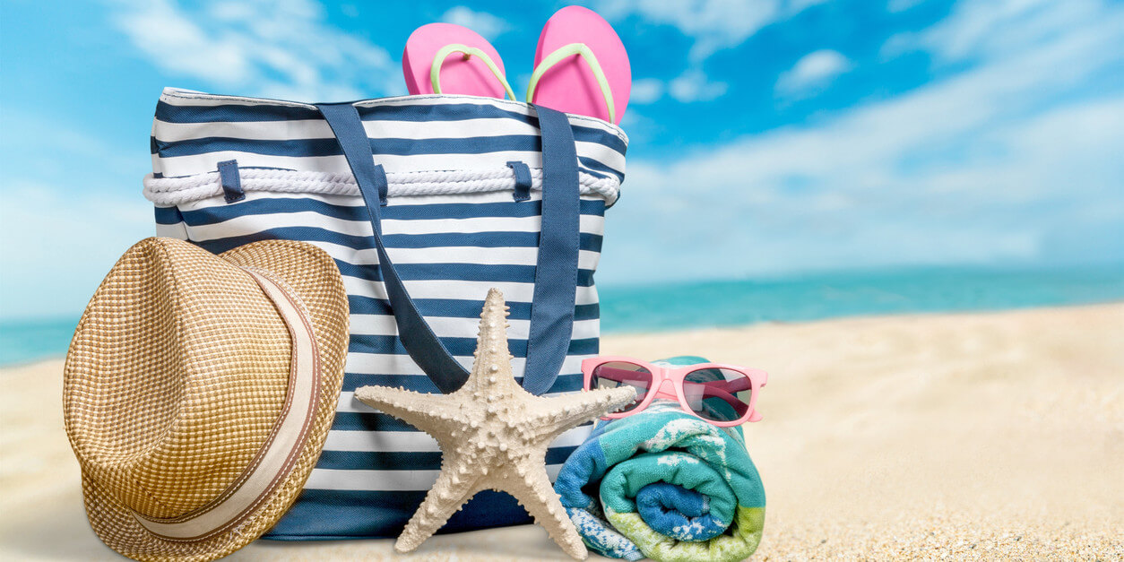 Tote bag on beach with hat, towel, and sandals