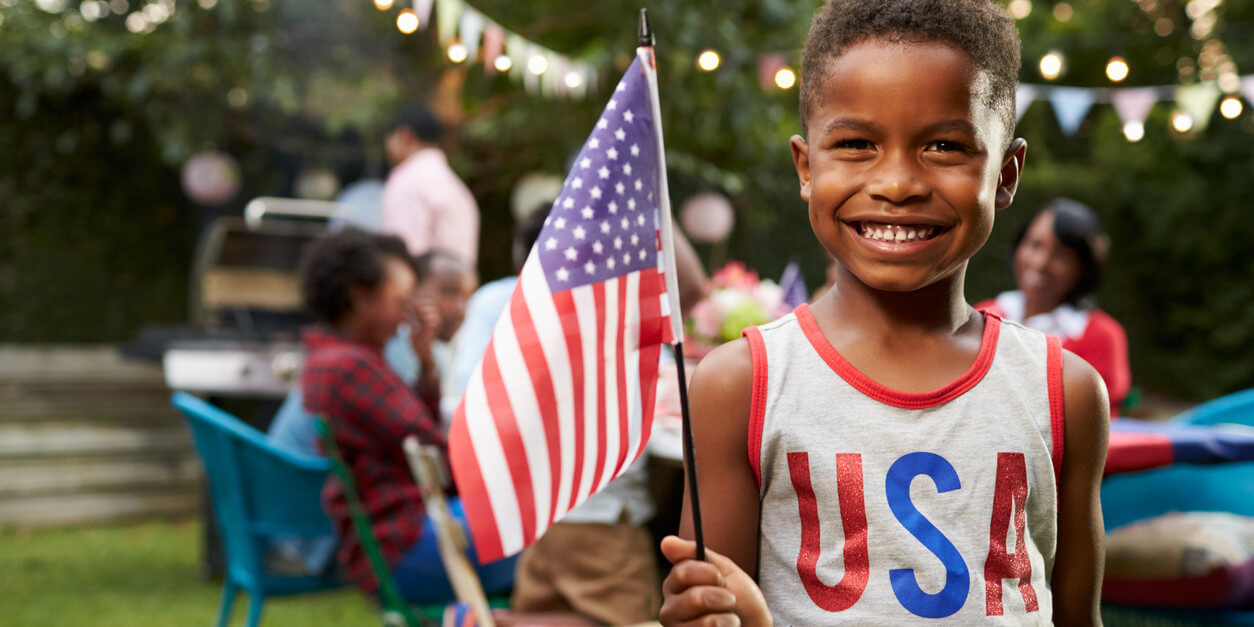 Child wearing a screen printed USA tank top holding an american flag