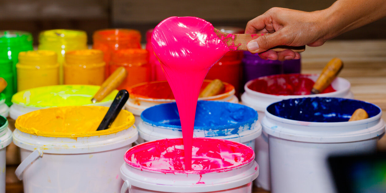 person scooping pink plastisol ink out of a bucket