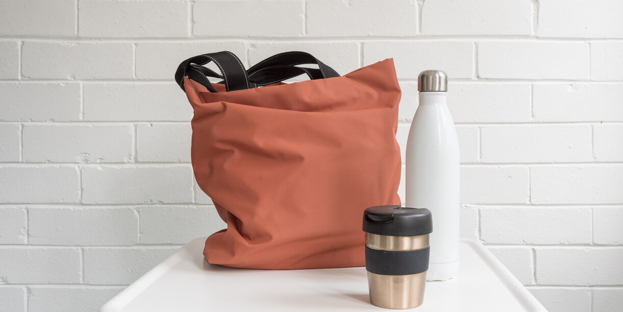 tote, metal coffee cup, and a metal water bottle on a table